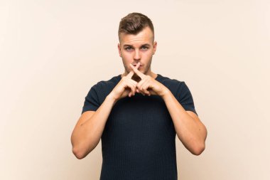 Izole arka plan üzerinde sessizlik jest bir işaret gösteren genç yakışıklı sarışın adam