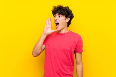 Ağzı tamamen açık bağıran izole sarı duvar üzerinde genç adam