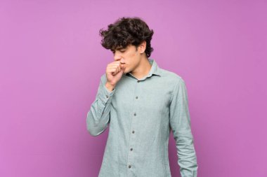 İzole edilmiş mor duvardaki genç adam öksürük ve kötü hissetmekten acı çekiyor.