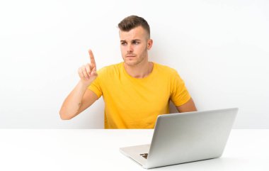 Young blonde man in a table with a laptop touching on transparent screen