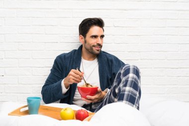 Sabahlık ve kahvaltı ile yatakta Adam