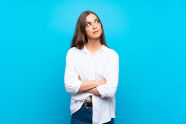 Karışık yüz ifadesi ile izole mavi arka plan üzerinde genç kadın