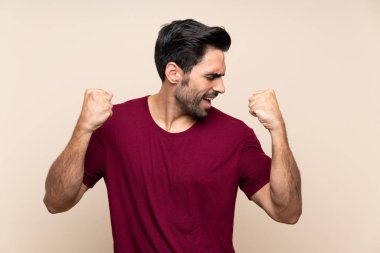 İzole arka plan üzerinde yakışıklı genç adam bir zafer kutluyor