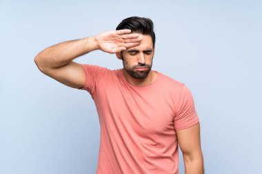 Yorgun ve hasta ifade ile izole mavi arka plan üzerinde pembe gömlek yakışıklı genç adam