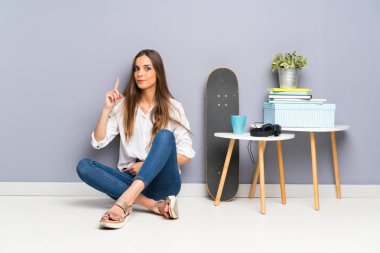 Yerde oturan genç bayan işaret parmağıyla işaret etmek harika bir fikir.