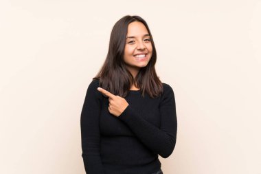 Bir ürün sunmak için yan işaret izole arka plan üzerinde beyaz kazak ile genç esmer kadın