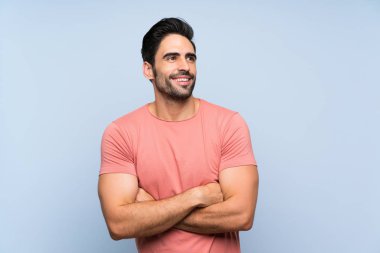 Izole mavi arka plan üzerinde pembe gömlek yakışıklı genç adam gülümserken yukarı bakıyor