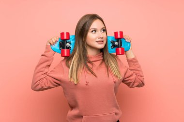 Izole pembe arka plan üzerinde paten ile Genç kız