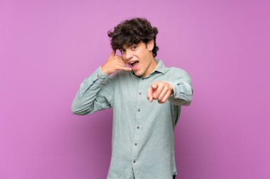 Izole mor duvar üzerinde genç adam telefon jest yapma ve ön işaret