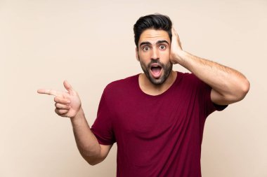 İzole arka plan üzerinde yakışıklı genç adam şaşırttı ve tarafına parmak işaret