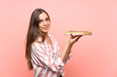 İzole pembe duvar üzerinde pizza tutan genç kadın