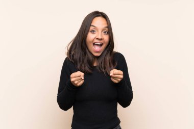 Izole arka plan üzerinde beyaz kazak ile genç esmer kadın kazanan pozisyonda bir zafer kutluyor