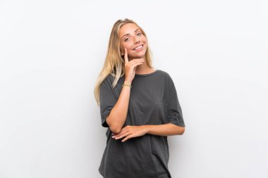 Sarışın genç kadın izole beyaz arka plan üzerinde bir fikir düşünürken yukarı bakarken