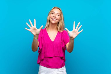 Izole mavi arka plan üzerinde Sarışın genç kadın parmakları ile on sayma