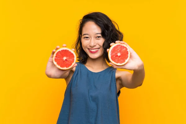 Ung Asiatisk Tjej Som Håller Grapefrukt Över Isolerad Orange Bakgrund — Stockfoto