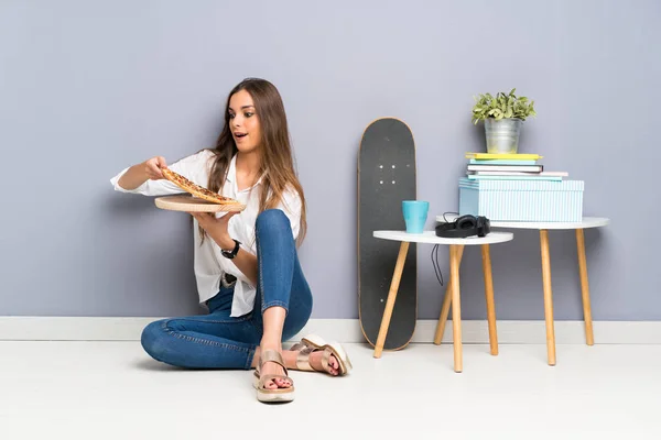 Jeune femme assise par terre avec une pizza — Photo