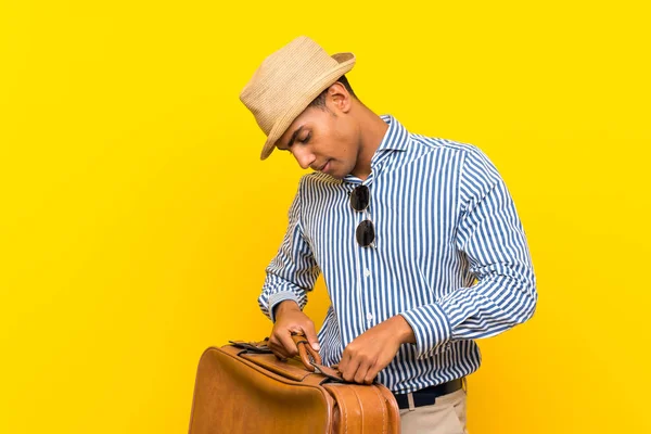 Bruna uomo in possesso di una valigetta vintage su isolato sfondo giallo — Foto Stock