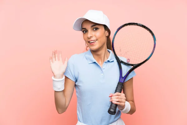 孤立したピンクの壁の上に若いテニスプレーヤーの女性は幸せな表情で手で敬礼 — ストック写真