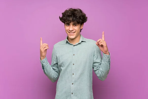 Молодий Чоловік Над Ізольованою Фіолетовою Стіною Вказує Чудову Ідею — стокове фото