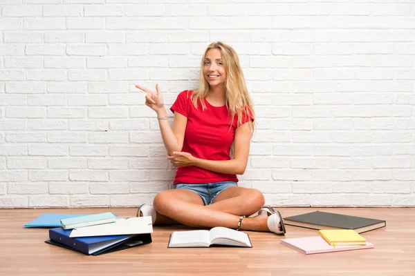 Joven Estudiante Rubia Con Muchos Libros Suelo Apuntando Con Dedo — Foto de Stock