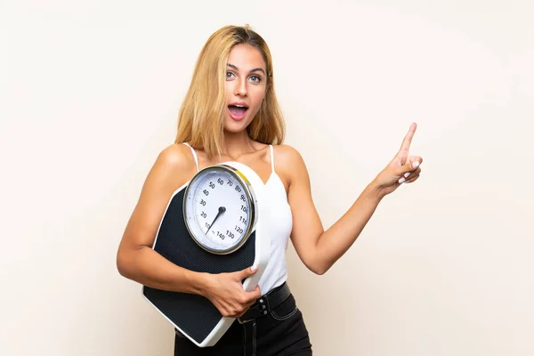 Mujer rubia joven con máquina de pesaje apuntando hacia el lateral — Foto de Stock