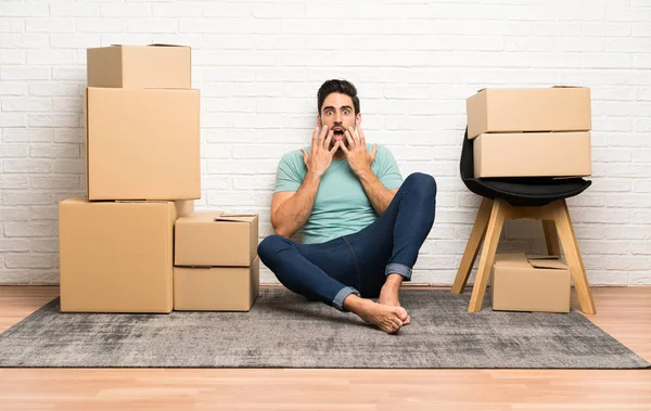 stock image Handsome young man moving in new home among boxes with surprise facial expression