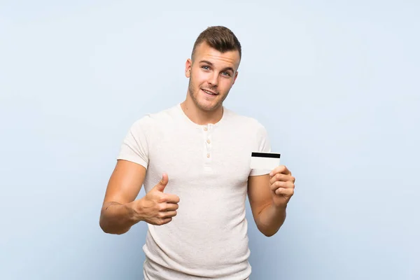 Młody Przystojny Blond Człowiek Białym Tle Niebieskim Posiadania Karty Kredytowej — Zdjęcie stockowe