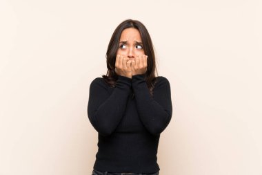 Izole arka plan sinir üzerinde beyaz kazak ile genç esmer kadın ve ağıza ellerini koyarak korkmuş