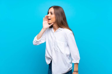 Izole mavi arka plan üzerinde genç kadın lateral ağız geniş açık bağırarak