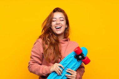 Izole sarı arka plan üzerinde paten ile Genç kızıl saçlı kız