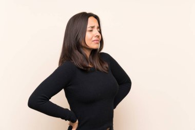 Bir çaba yapmış olması için sırt ağrısı muzdarip izole arka plan üzerinde beyaz kazak ile genç esmer kadın