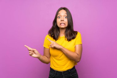 Izole arka plan üzerinde genç esmer kız korkmuş ve yan işaret