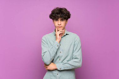 İzole mor duvar üzerinde genç adam ön bakıyor