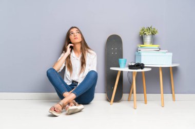 Genç bir kadın yerde oturmuş bir fikir düşünüyor.