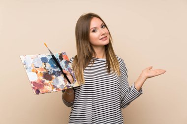 Genç kız avuç üzerinde copyspace hayali tutan izole arka plan üzerinde bir palet tutan