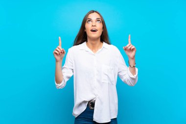 Izole mavi arka plan üzerinde genç kadın şaşırttı ve işaret