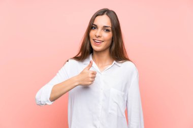 Soyutlanmış pembe arka planda genç bir kadın baş parmak işareti yapıyor.