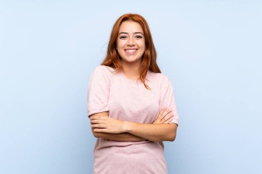 Izole mavi arka plan üzerinde genç redhead kız kollarını ön konumda geçti tutarak