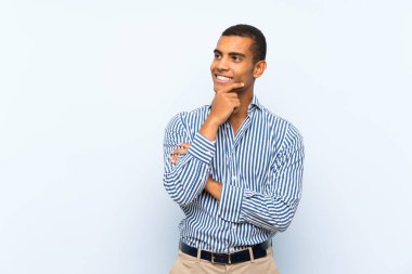 Izole mavi arka plan üzerinde genç yakışıklı esmer adam yan bakıyor