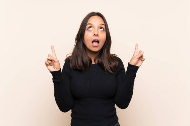 Izole arka plan üzerinde beyaz kazak ile genç esmer kadın şaşırttı ve işaret