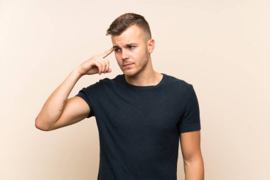 Izole arka plan üzerinde genç yakışıklı sarışın adam kafasına parmak koyarak delilik jest yapma