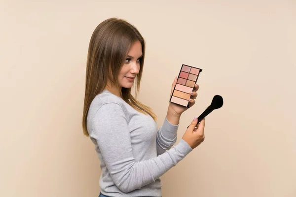 Chica adolescente con paleta de maquillaje sobre fondo aislado — Foto de Stock