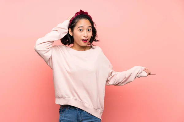 Asiatische Junge Frau Über Isolierten Rosa Hintergrund Überrascht Und Zeigt — Stockfoto