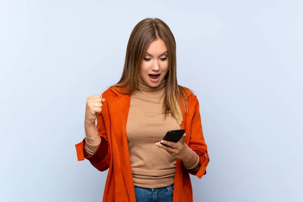 Ragazza Adolescente Con Cappotto Isolato Sfondo Blu Sorpreso Invio Messaggio — Foto Stock