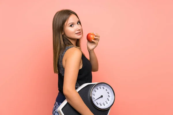 Teenager girl with weighing machine over isolated background
