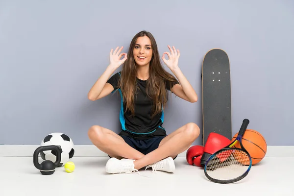 Młoda Kobieta Sportowa Siedzi Podłodze Pokazując Znak Palcami — Zdjęcie stockowe