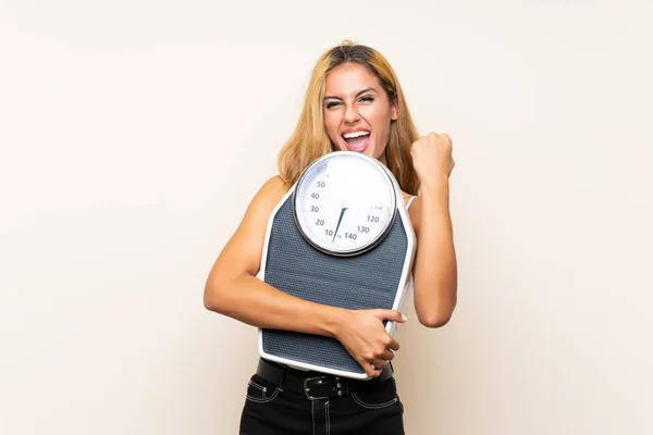 Mujer rubia joven con máquina de pesaje sobre fondo aislado — Foto de Stock