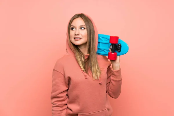 Teenager girl with skate over isolated pink background — Stock Photo, Image