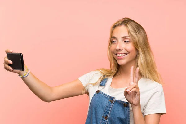 Ευτυχισμένος ξανθιά νεαρή γυναίκα με ένα κινητό τηλέφωνο κάνοντας μια selfie — Φωτογραφία Αρχείου
