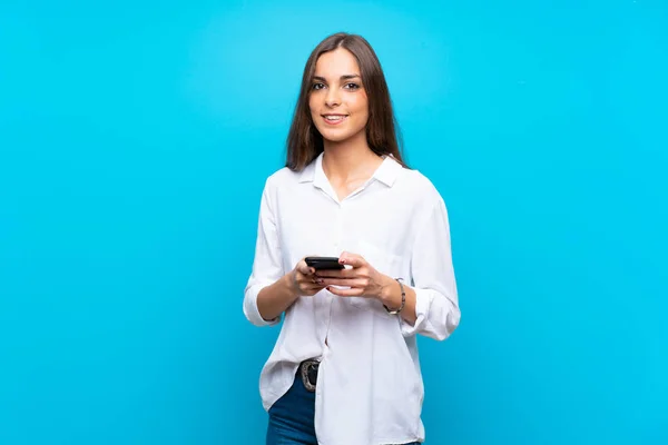 Mujer Joven Sobre Fondo Azul Aislado Enviando Mensaje Con Móvil —  Fotos de Stock